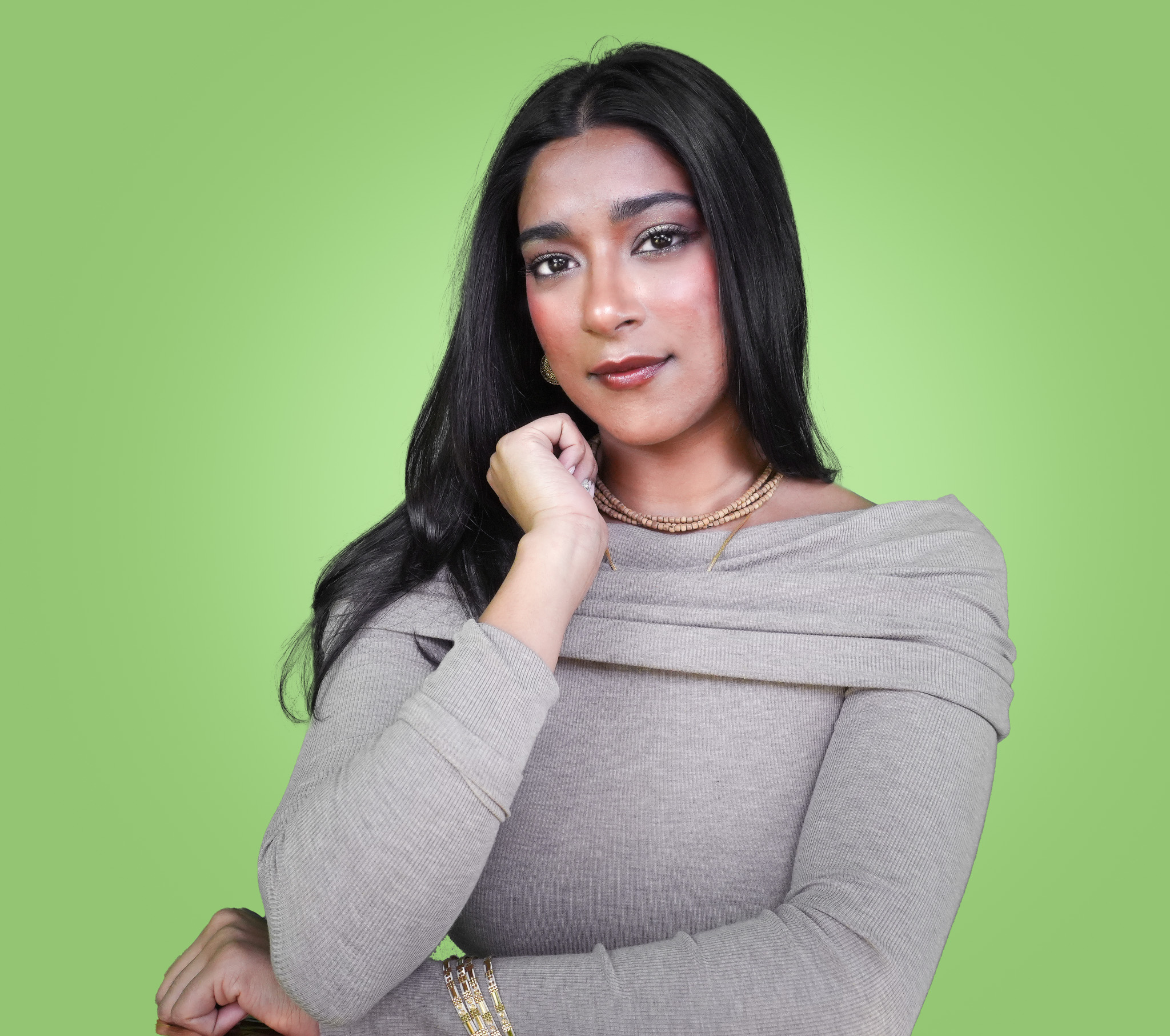 Kirtaniya, wearing a vibrant pink traditional dress adorned with beadwork, her arms crossed in front of her. Her composed expression and appearance convey a sense of peacefulness.